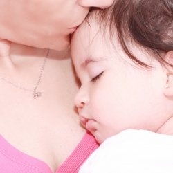 Mother kissing her baby girl's forehead